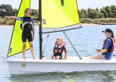 Slide: The Image of Children sailing on a 2024 RS Zest boat with bright yellow sails. - 3