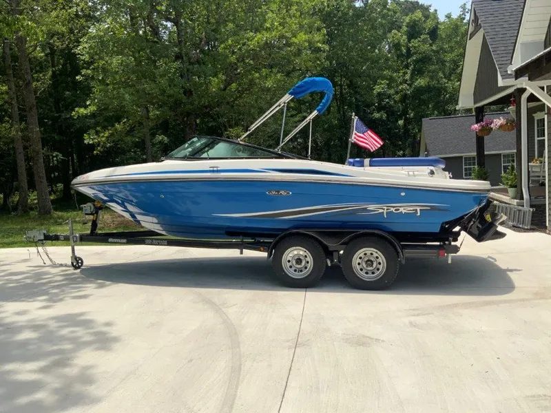 The Image of 2012 Sea Ray 205 Sport boat on trailer, parked in driveway with trees in background. - 0