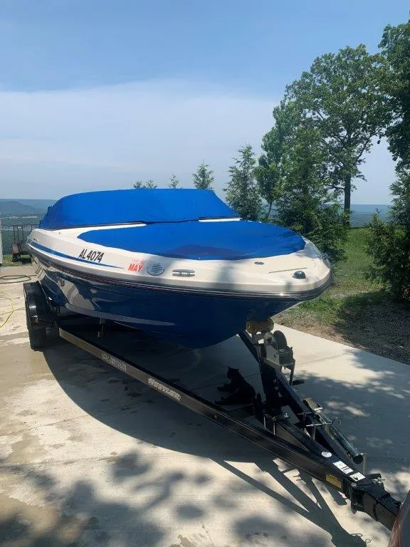 Slide: The Image of 2012 Sea Ray 205 Sport boat on trailer with blue cover, parked outdoors. - 10