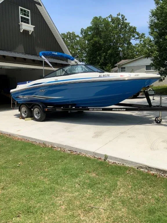 Slide: The Image of 2012 Sea Ray 205 Sport boat on trailer, parked in driveway near garage. - 2