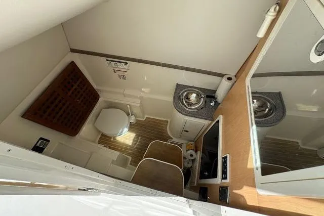 Slide: The Image of 2019 World Cat 320 DC boat bathroom with sink, toilet, and wooden flooring. - 21