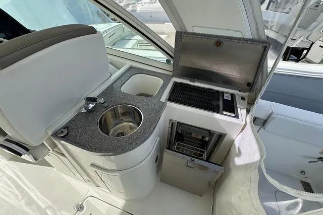 Slide: The Image of 2019 World Cat 320 DC boat interior with sink, grill, and mini fridge. - 44