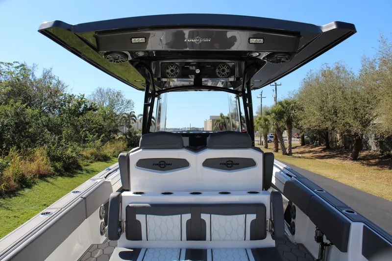 Slide: The Image of 2023 Fountain 34 SC boat interior with seating and canopy, surrounded by trees. - 18