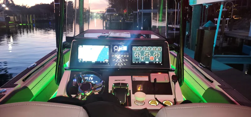 Slide: The Image of 2023 Fountain 34 SC boat dashboard with illuminated controls and navigation screens at dusk. - 21