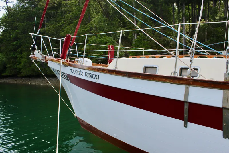 Slide: The Image of Sailboat "Phoenix Rising" on water, Skookum 53, 1981 model, with lush forest background. - 10