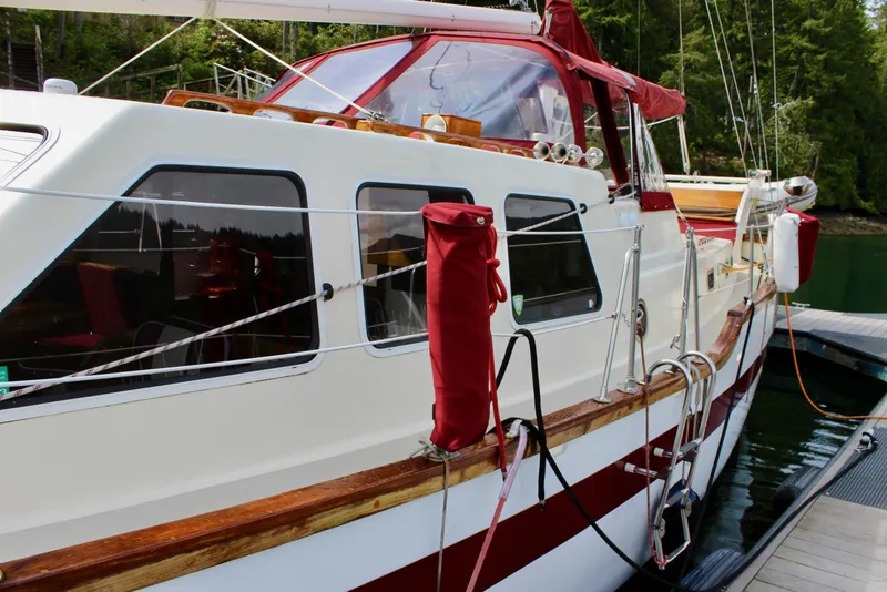 Slide: The Image of 1981 Skookum 53 yacht docked, featuring red accents and lush forest backdrop. - 11