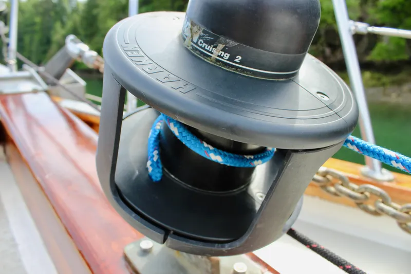 Slide: The Image of Winch on 1981 Skookum 53 sailboat with blue rope, surrounded by lush greenery. - 18