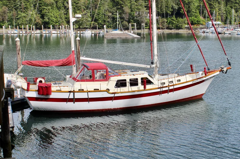 Slide: The Image of Sailboat "Skookum 53" from 1981 docked in a serene marina setting. - 2