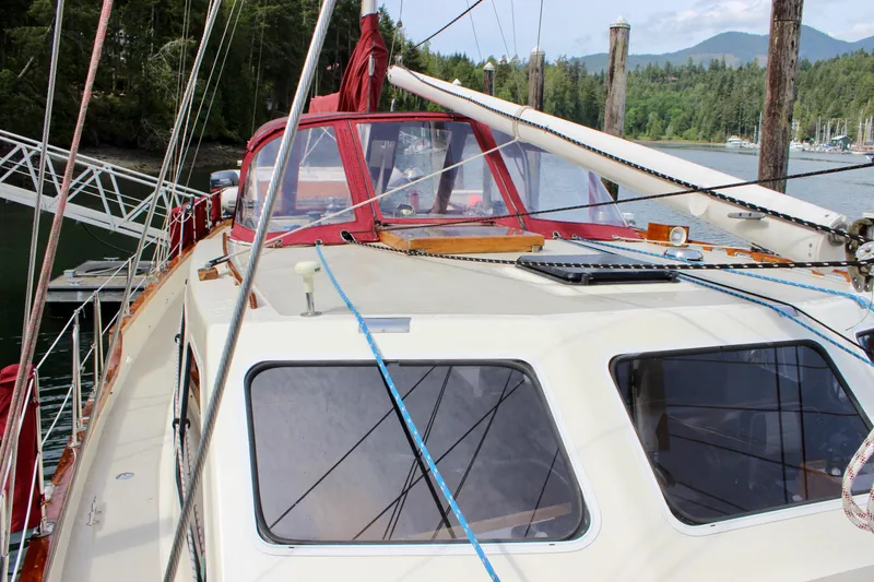 Slide: The Image of Sailboat Skookum 53, 1981 model, docked in a scenic marina with forested hills. - 23