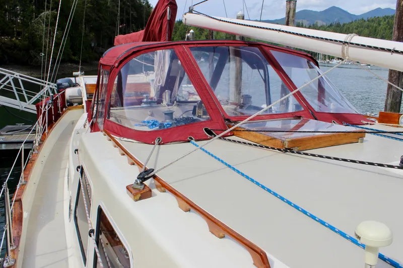 Slide: The Image of 1981 Skookum 53 sailboat with red canopy, docked in a scenic marina. - 25