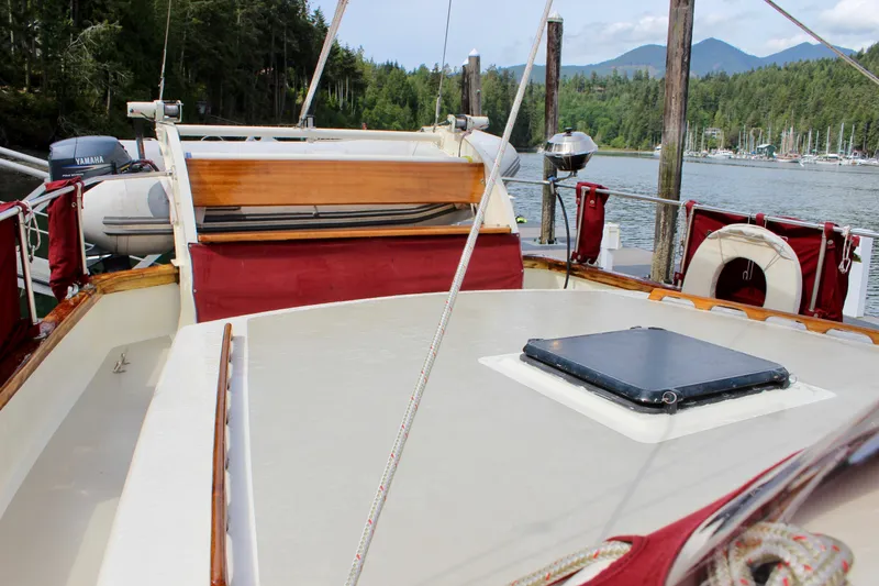 Slide: The Image of Sailboat deck of 1981 Skookum 53, docked in a scenic marina with forested backdrop. - 26