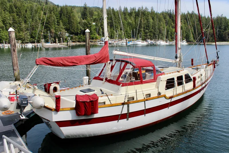 Slide: The Image of Sailboat docked in a serene marina, Skookum 53 model, 1981, with lush forest backdrop. - 3
