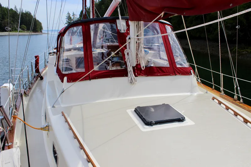Slide: The Image of Sailboat Skookum 53, 1981 model, with red trim, docked in a serene waterway. - 30
