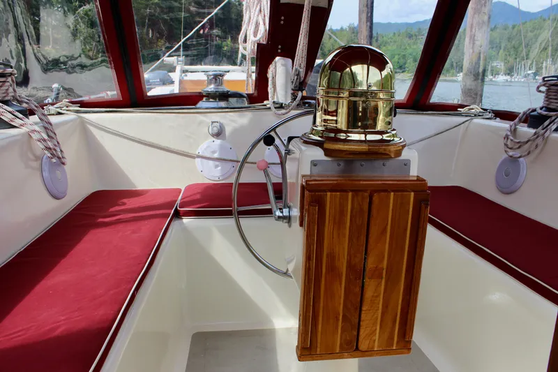 Slide: The Image of 1981 Skookum 53 sailboat cockpit with red cushions and wooden helm. - 36