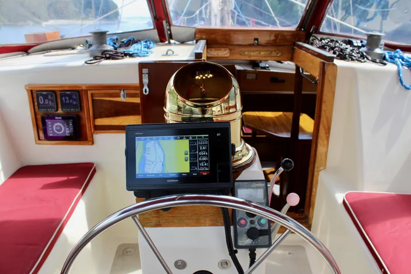 Slide: The Image of 1981 Skookum 53 sailboat cockpit with navigation equipment and red cushioned seating. - 37