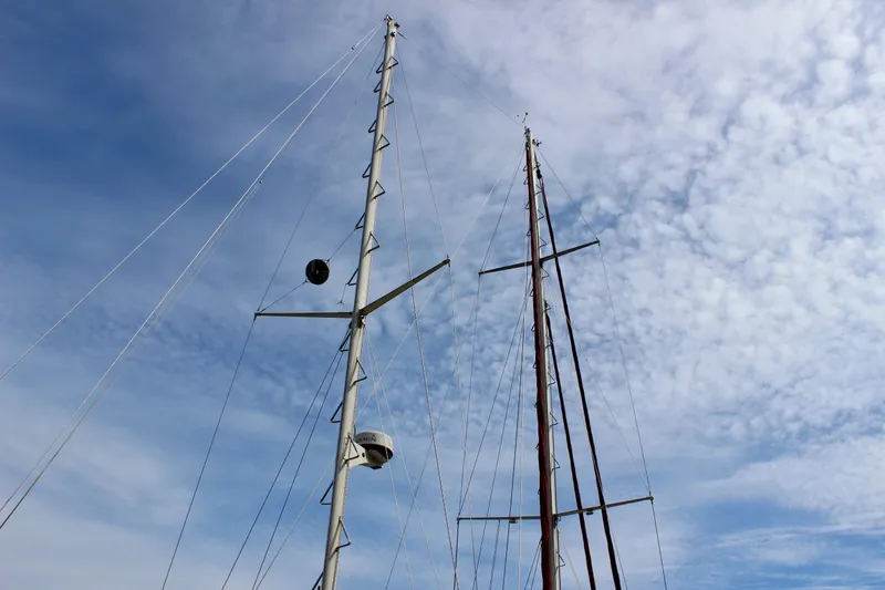 Slide: The Image of Masts of a 1981 Skookum 53 sailboat against a cloudy blue sky. - 6