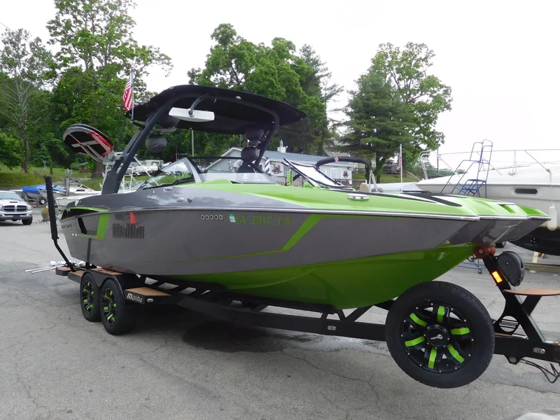 The Image of 2017 Malibu Wakesetter 24 MXZ boat on trailer, green and gray, parked outdoors. - 0