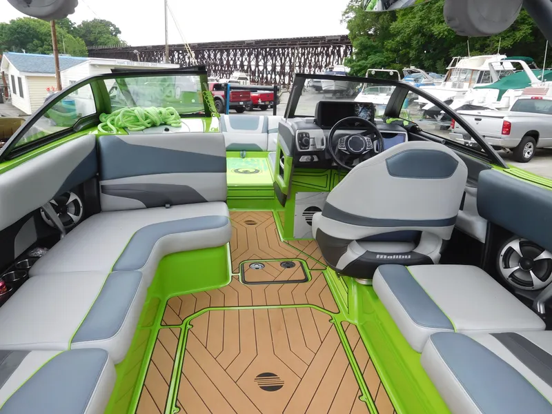 Slide: The Image of 2017 Malibu Wakesetter 24 MXZ interior with green and gray seating, wood-like flooring. - 19