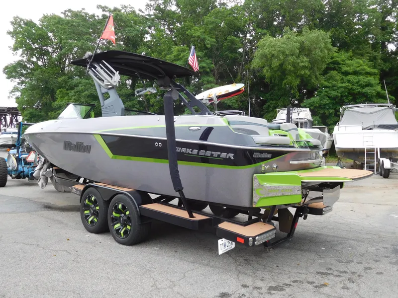 Slide: The Image of 2017 Malibu Wakesetter 24 MXZ boat on trailer, green and gray, parked outdoors. - 5
