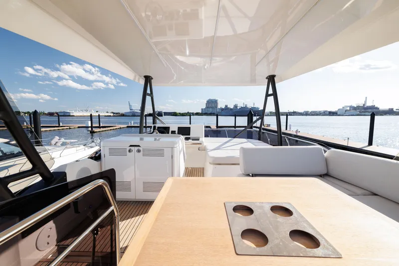 Slide: The Image of 2024 Prestige 520 yacht deck with seating and table, overlooking a scenic waterfront. - 10