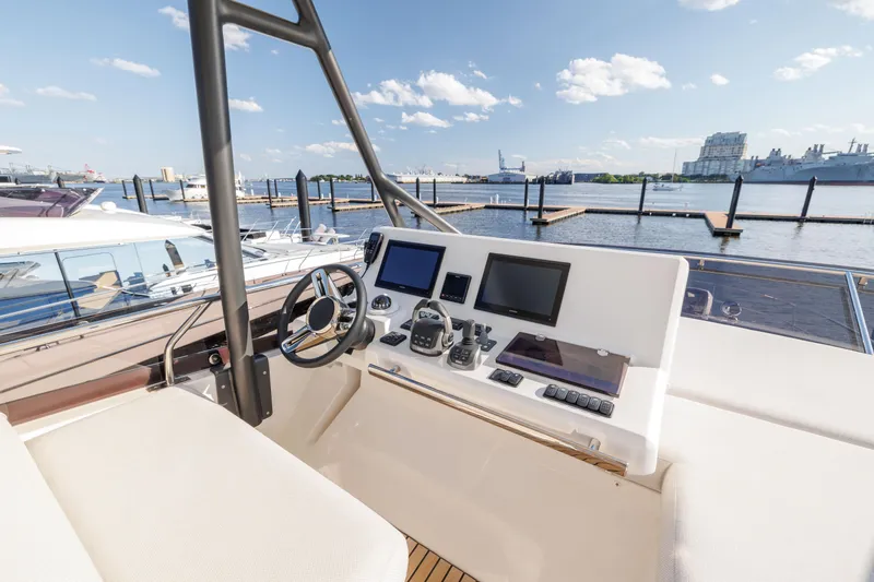 Slide: The Image of 2024 Prestige 520 yacht helm station with modern navigation equipment, docked at a marina. - 7