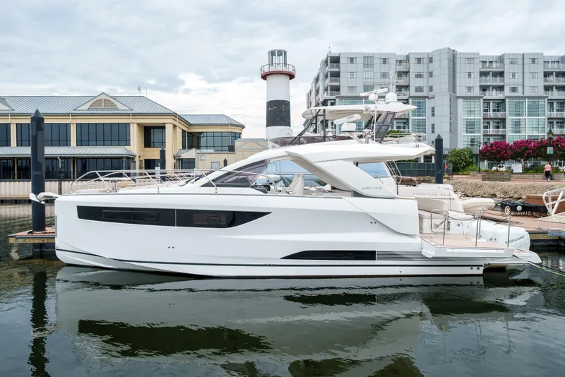 Slide: The Image of 2024 Jeanneau DB|43 Outboard yacht docked near modern buildings and lighthouse. - 0