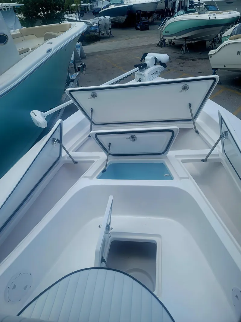 Slide: The Image of 2025 Piranha Casador B2200 boat with open storage compartments, docked among other boats. - 16