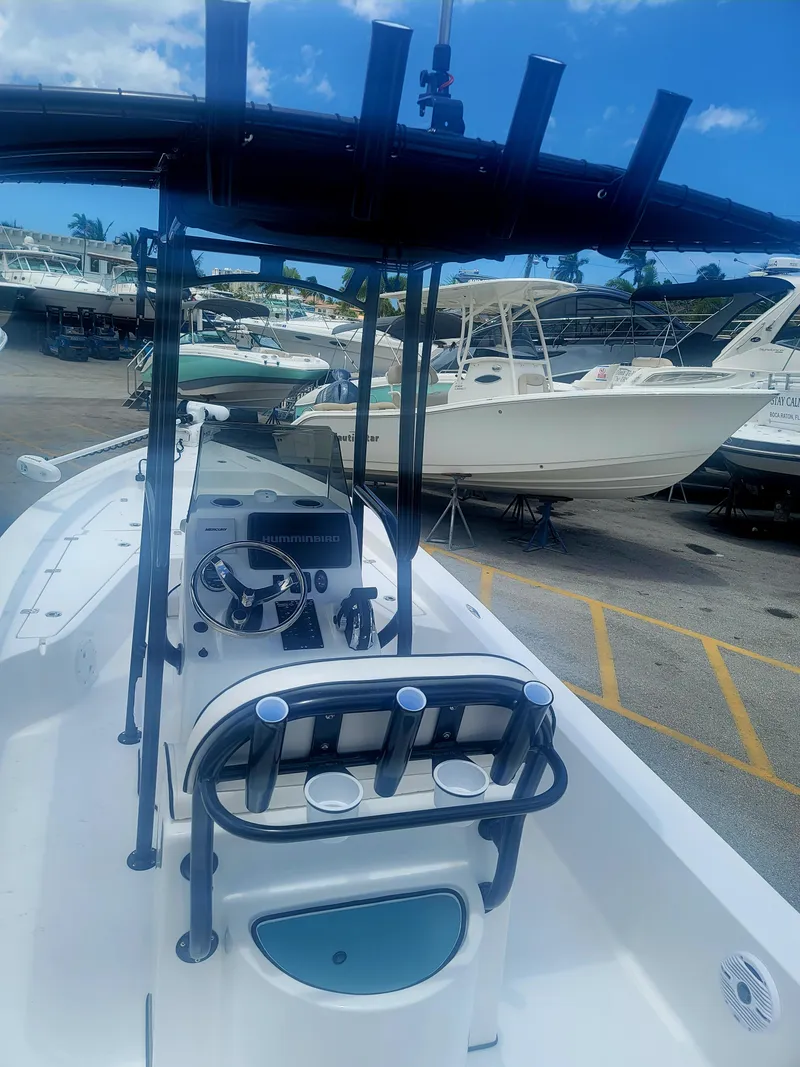 Slide: The Image of 2025 Piranha Casador B2200 boat with T-top, docked in a marina under a blue sky. - 6