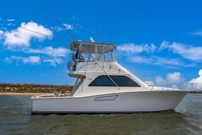 Slide: The Image of 2002 Cabo Convertible Painted boat on water with blue sky background. - 0