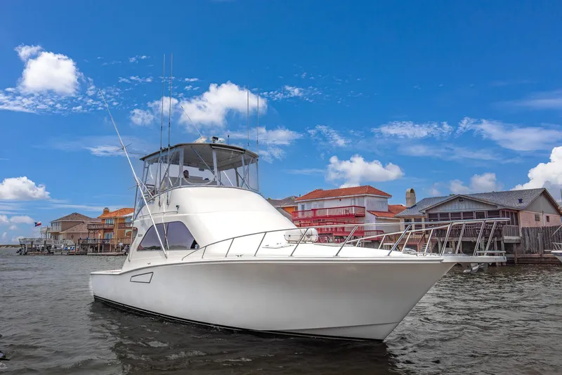 Slide: The Image of 2002 Cabo Convertible Painted boat docked near colorful waterfront houses. - 1