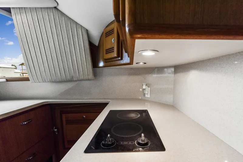 Slide: The Image of 2002 Cabo Convertible Painted yacht kitchen with stovetop and wooden cabinets. - 22