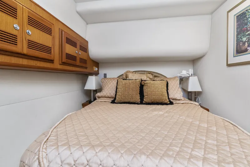 Slide: The Image of 2002 Cabo Convertible Painted boat interior bedroom with beige bedding and wooden cabinets. - 32