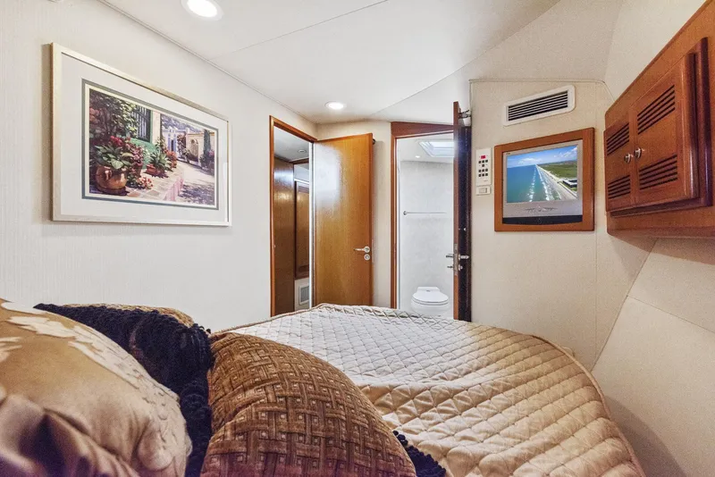 Slide: The Image of 2002 Cabo Convertible Painted yacht bedroom with TV, artwork, and ensuite bathroom. - 35