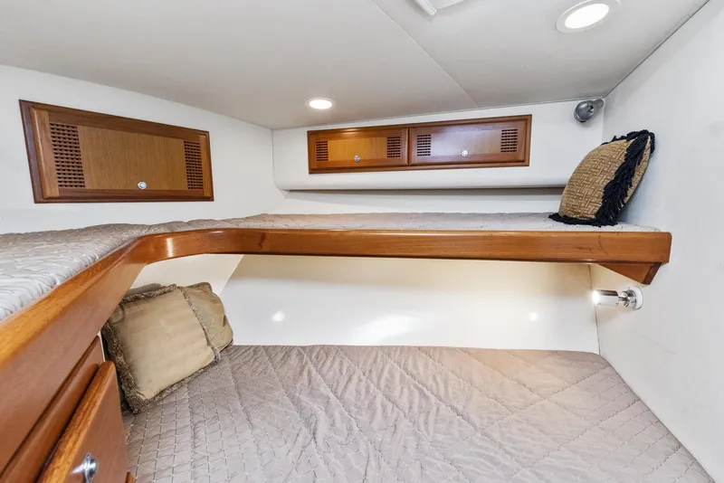 Slide: The Image of 2002 Cabo Convertible Painted boat interior with wooden cabinets and cozy bedding. - 39
