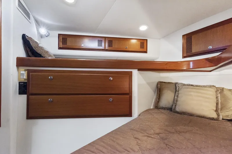 Slide: The Image of 2002 Cabo Convertible Painted boat interior with wooden cabinets and cozy bedding. - 42