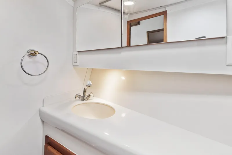 Slide: The Image of 2002 Cabo Convertible Painted boat bathroom with white sink and mirror. - 44