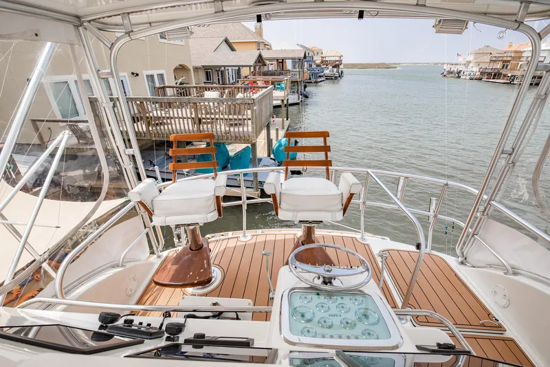 Slide: The Image of 2002 Cabo Convertible Painted boat with wooden deck and waterfront view. - 9