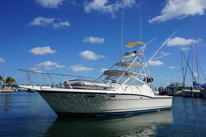 The Image of 1985 Hatteras 36 Convertible yacht docked in a marina under a clear blue sky. - 0