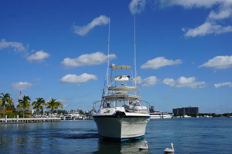 Slide: The Image of 1985 Hatteras 36 Convertible boat docked in a marina under a clear blue sky. - 14