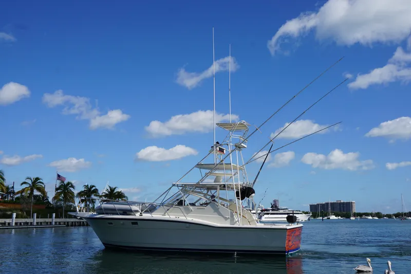 Slide: The Image of 1985 Hatteras 36 Convertible boat on calm water with blue sky background. - 16