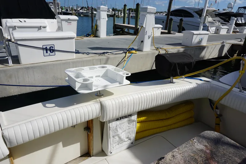 Slide: The Image of 1985 Hatteras 36 Convertible boat docked, featuring white seating and fishing rod holders. - 39