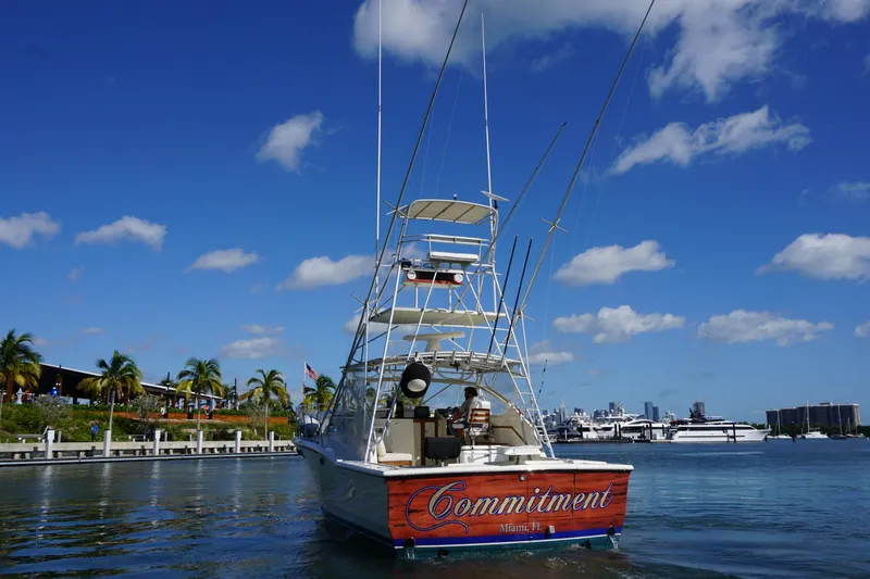 Slide: The Image of 1985 Hatteras 36 Convertible boat named Commitment docked in a marina under a clear blue sky. - 4