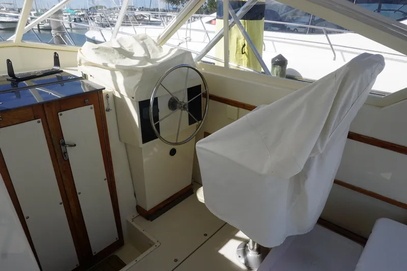 Slide: The Image of 1985 Hatteras 36 Convertible boat helm station with covered captain's chair and steering wheel. - 42