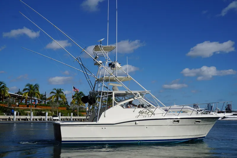 Slide: The Image of 1985 Hatteras 36 Convertible boat cruising in a marina with palm trees. - 8
