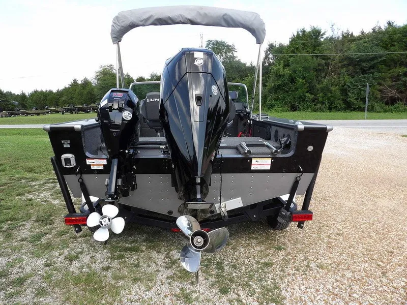 Slide: The Image of 2019 Lund 1975 Pro V Sport boat with dual outboard motors, parked on gravel. - 6