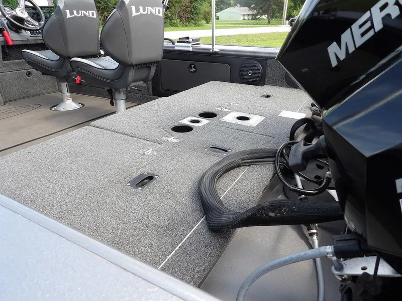 Slide: The Image of 2019 Lund 1975 Pro V Sport boat interior with seating and motor, showcasing fishing deck features. - 7
