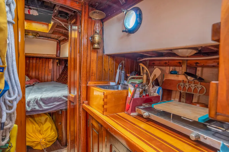 Slide: The Image of Interior of a 1950 Custom Cornu Sloop with wooden cabinetry and cozy sleeping quarters. - 14