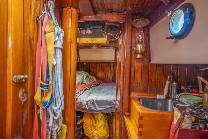 Slide: The Image of Interior of a 1950 Custom Cornu Sloop with wooden finishes, bed, and sink. - 15