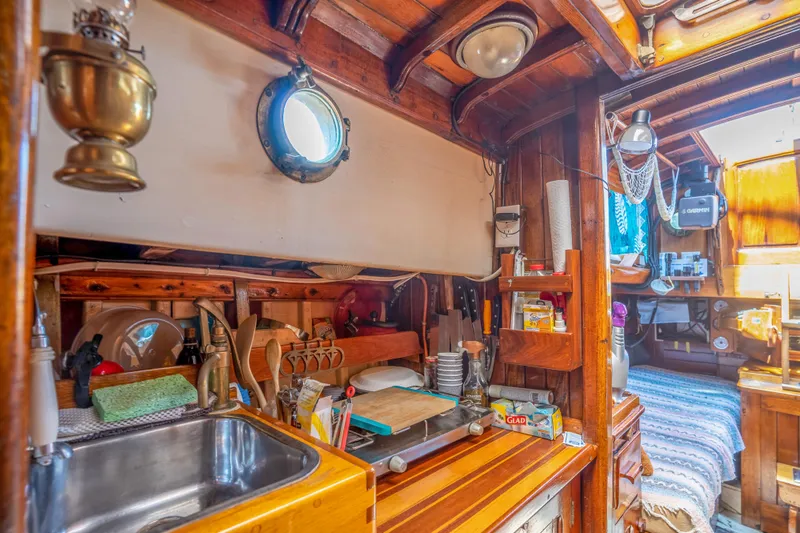 Slide: The Image of 1950 Custom Cornu Sloop interior with wooden cabinetry, sink, and cozy sleeping area. - 19