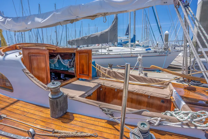 Slide: The Image of 1950 Custom Cornu Sloop sailboat with wooden deck and open cabin at marina. - 4
